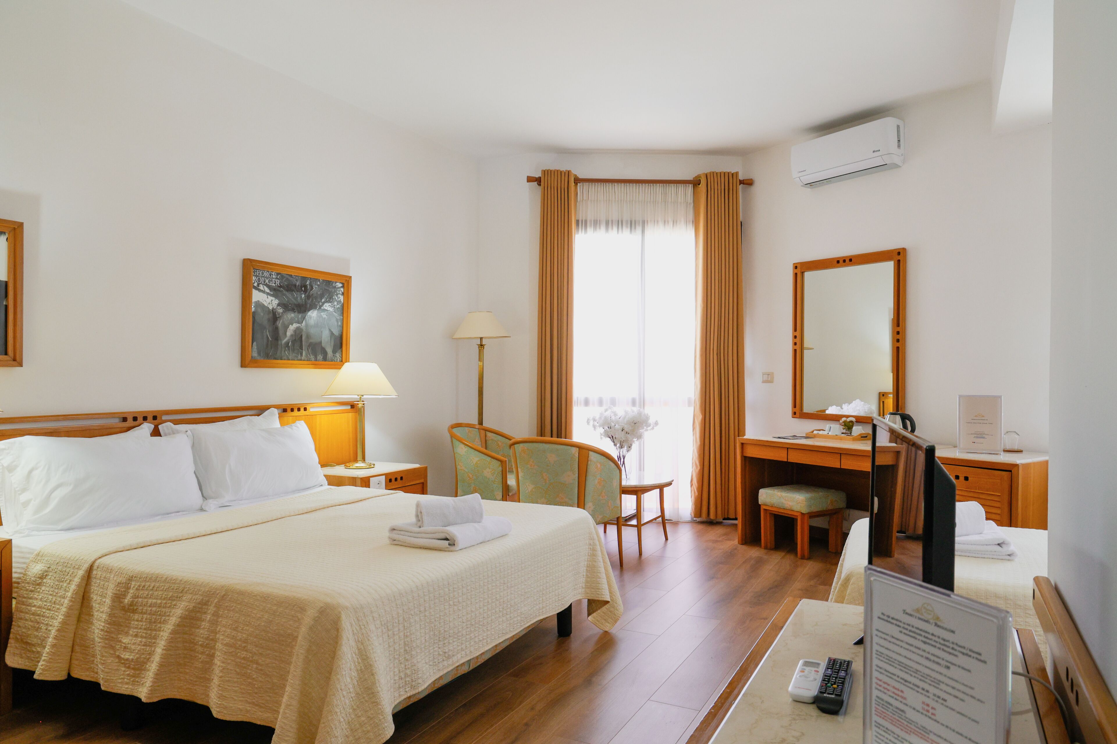 Habitación de hotel con cama, escritorio, silla y ventana con cortinas.