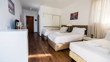 A hotel room with two beds, a desk, a chair, a lamp, and a small plant.