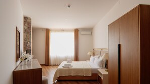 Habitación de hotel con cama, mesita de noche, lámpara, armario y una pared decorativa de piedra.