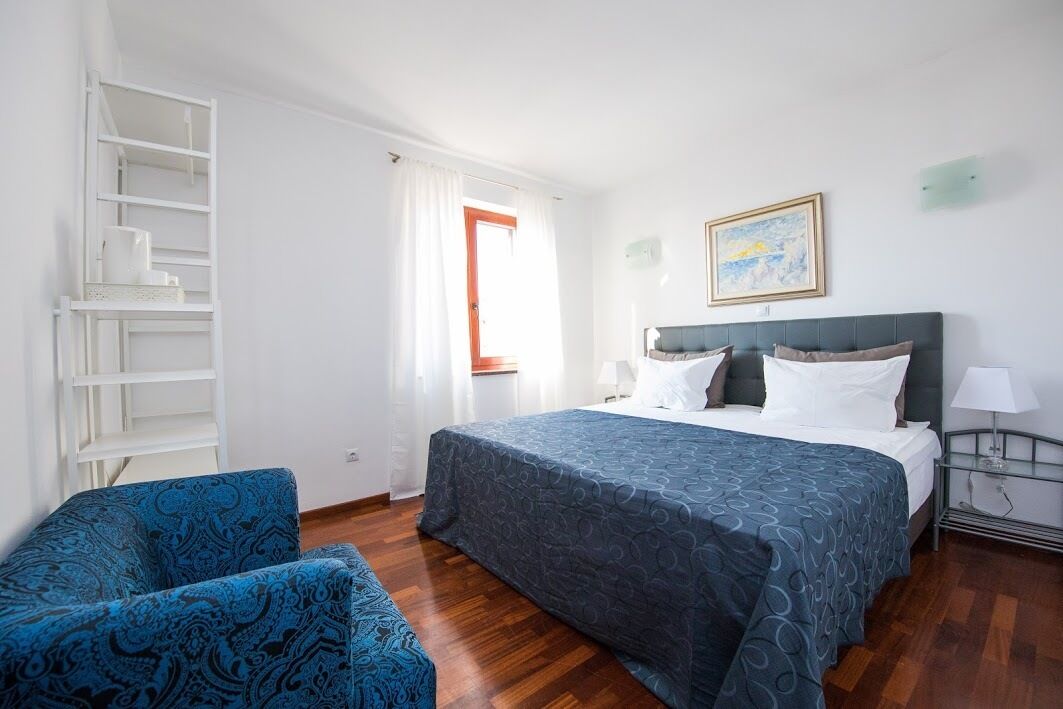 Una habitación de hotel con una cama, una silla, una estantería y un cuadro en la pared.