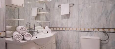 A bathroom with a marble sink, a toilet, and a mirror.