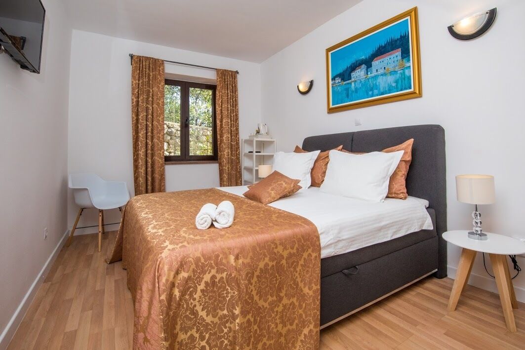 Une chambre d’hôtel avec un lit, un bureau, une chaise, une fenêtre avec des rideaux, un tableau au mur et une lampe sur une table de chevet.