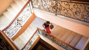 A multi-level interior with a staircase featuring ornate metal railings and a person descending. - Villa Dard (Dubrovnik)