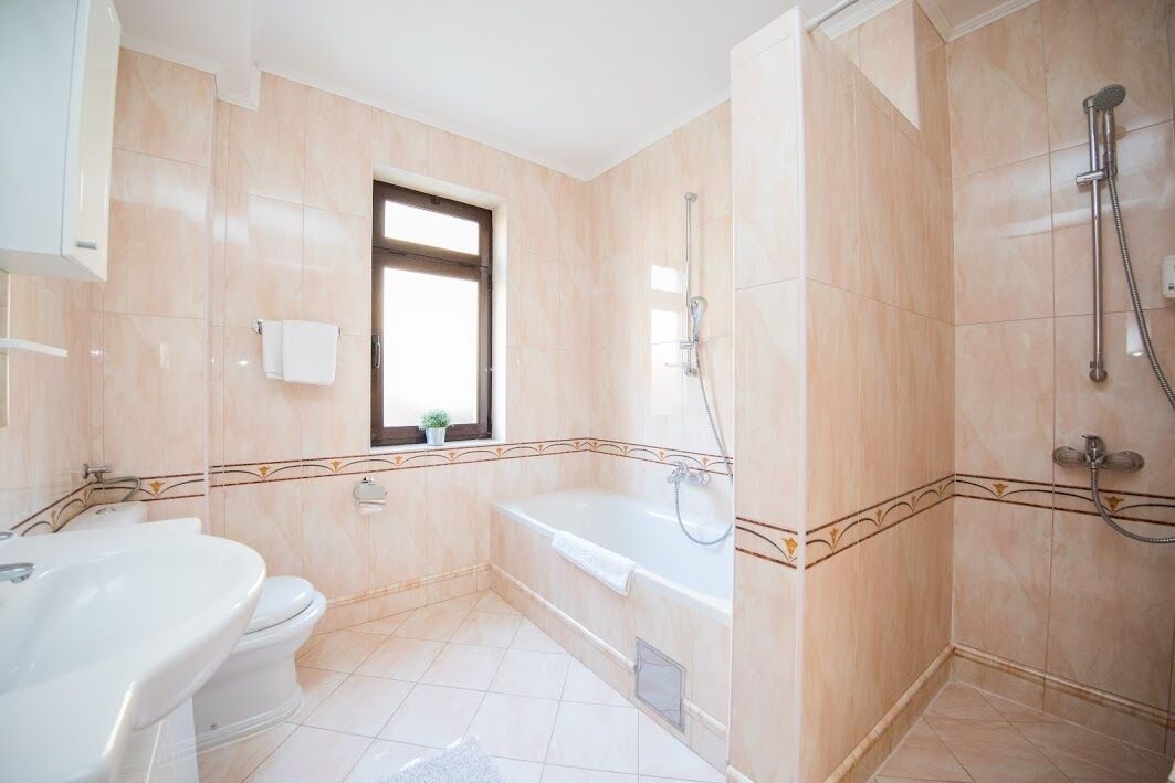 A bathroom with a bathtub, a toilet, and a shower area.
