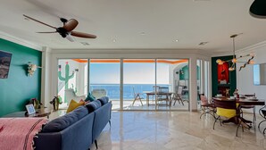 Un vaste espace de vie comprenant un grand canapé, une table à manger et un ventilateur de plafond.