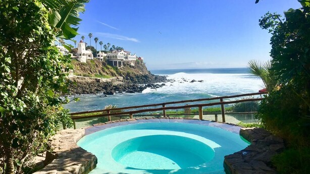 Une piscine avec vue sur l’océan et un bâtiment situé au bord d’une falaise.