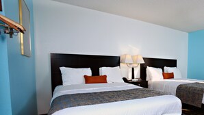 Camera d'albergo con due letti, un comodino con una lampada e un quadro appeso al muro.