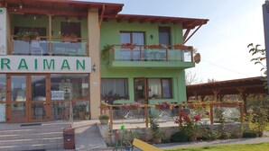 A restaurant named "Pensiune Restaurant" with a sign "CARAMAN" and outdoor seating with potted plants. - Pensiunea Caraiman (Codlea)
