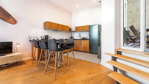 A modern kitchen with wooden cabinets, a stainless steel refrigerator, and a dining area with a table and chairs.