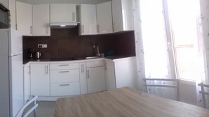 Una cocina compacta con armarios blancos, estufa integrada y un lavamanos.