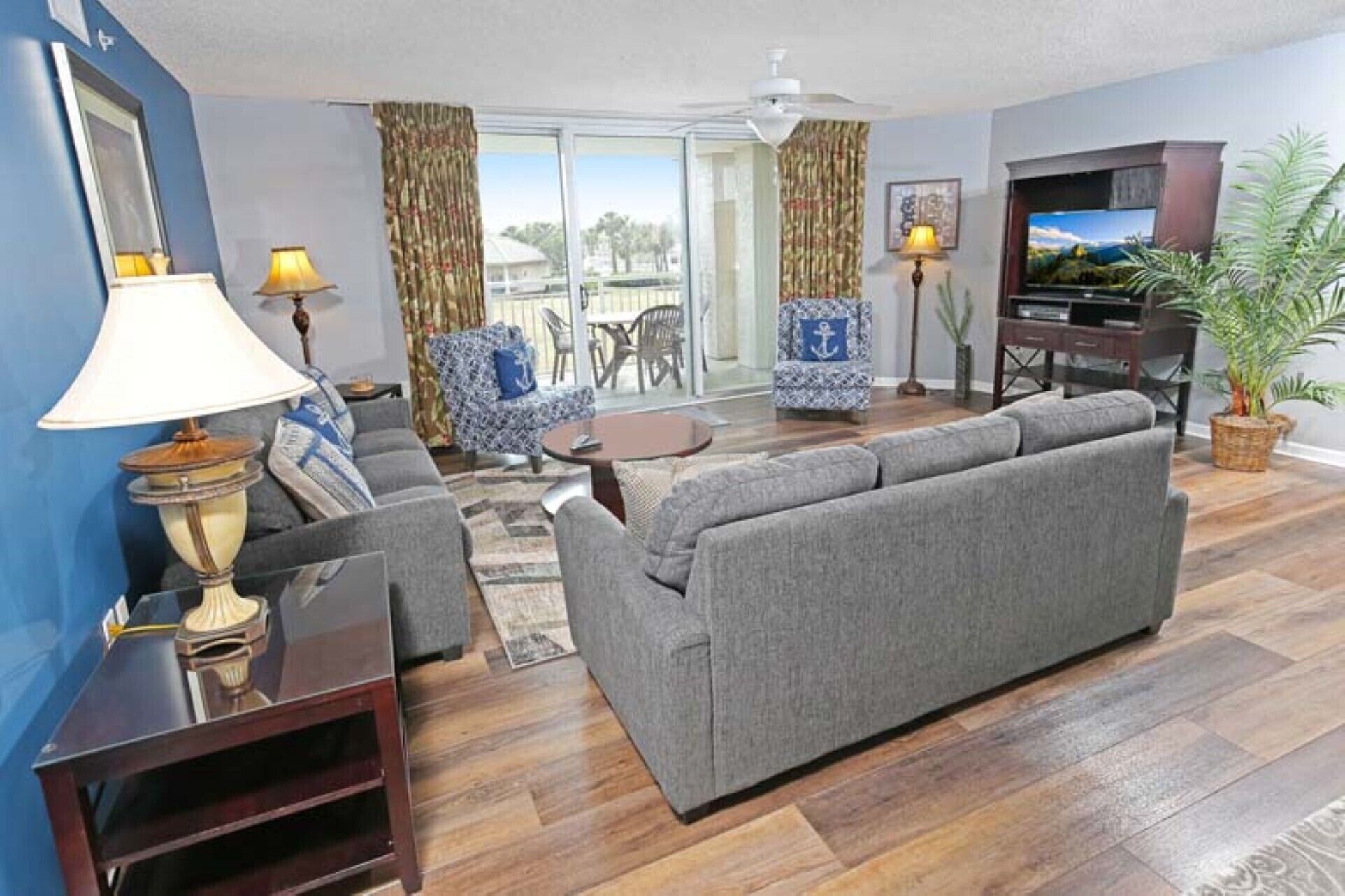 Ein Wohnzimmer mit einem grauen Sofa, einem Fernseher und einer Pflanze.