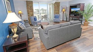Una sala de estar con un sofá gris, un televisor y una planta.