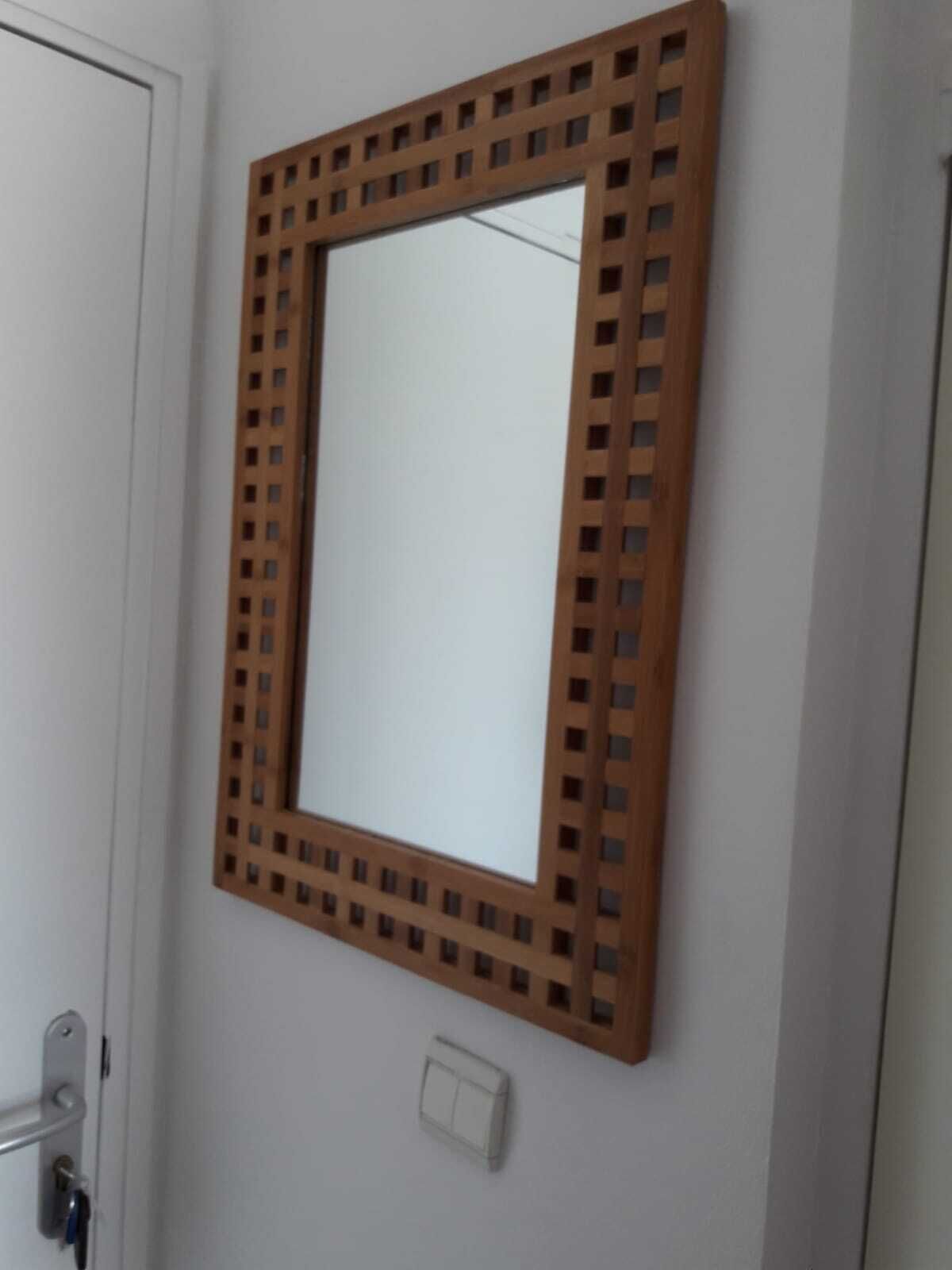 Ein Badezimmer mit einem spiegelnden Wandbild aus Holz, einer Tür und einem Lichtschalter.