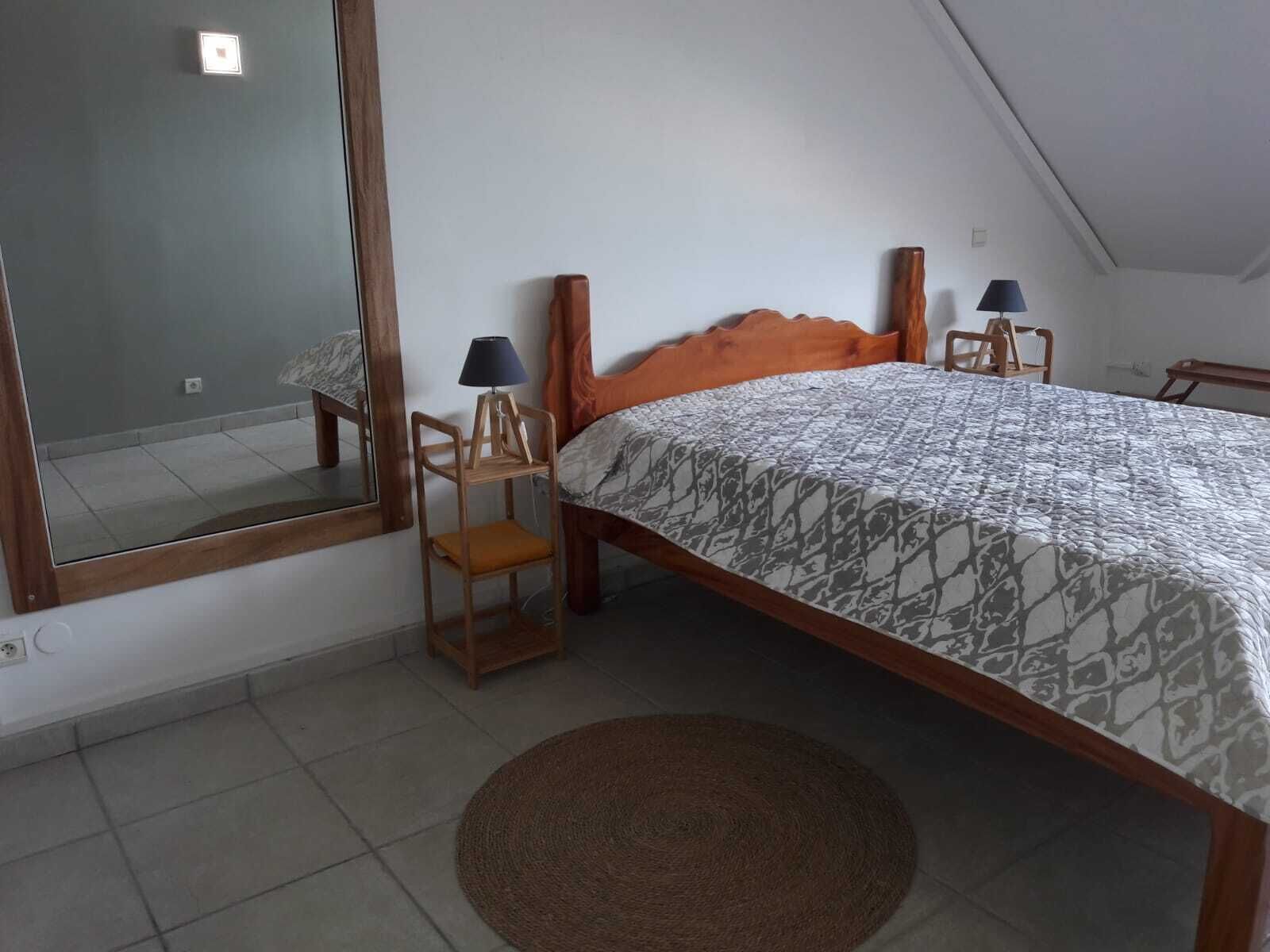A bedroom with a bed, two nightstands, a mirror, and a brown rug.