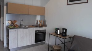 A compact kitchen with a built-in oven, a coffee maker, and a small table. - Charming duplex with no water shut-off (Le Gosier)