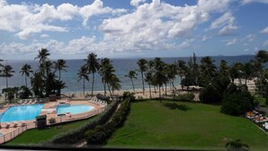A resort with a pool, palm trees, and a beach view. - Charming duplex with no water shut-off (Le Gosier)