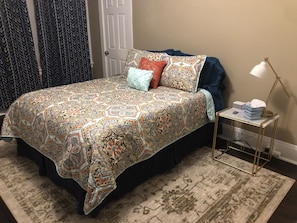 A bed with a patterned bedspread, a bedside table with a lamp, and a rug. - House in Soulard near Downtown, Arch, Busch Stadium and anheuser busch brewery (St. Louis)