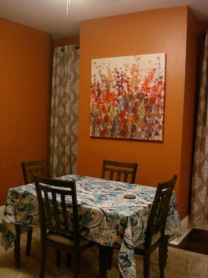 A dining area with a table covered in a patterned tablecloth, surrounded by wooden chairs. - House in Soulard near Downtown, Arch, Busch Stadium and anheuser busch brewery (St. Louis)