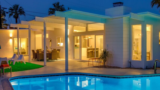 A modern house with a swimming pool, outdoor dining area, and a covered patio. - For The Record (Palm Springs)