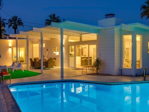 A modern house with a swimming pool, outdoor dining area, and a covered patio. - For The Record (Palm Springs)