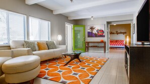 A modern living room with a sofa, coffee table, and a vibrant orange rug. - San Lucas Hideout (Palm Springs)