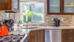 A modern kitchen with a stainless steel dishwasher, a coffee maker, and a gas stove. - San Lucas Hideout (Palm Springs)