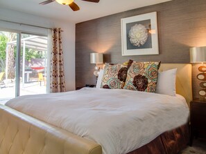 A large bed with a headboard, a ceiling fan, and a wall-mounted lamp. - Modern Ranch Heaven (Palm Springs)