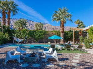 A pool area with lounge chairs, a hammock, and a fire pit.