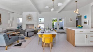 A modern living room with a sofa, coffee table, and dining area with yellow chairs. - Mid Mod Sunsation (Palm Springs)