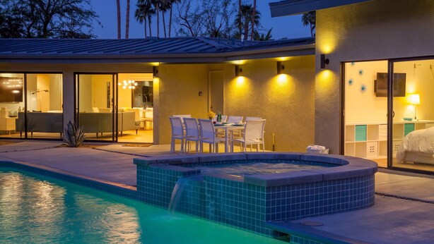 A modern pool area with a hot tub, outdoor seating, and a well-lit patio. - Mid-century Deluxe (Palm Springs)