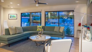 A modern living room with a sectional sofa, a round coffee table, and a white chair. - Mid-century Deluxe (Palm Springs)