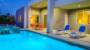 A modern outdoor pool area with lounge chairs and a dining table.