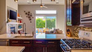 A modern kitchen with dark wood cabinets, a stainless steel range, and a large window overlooking a patio.