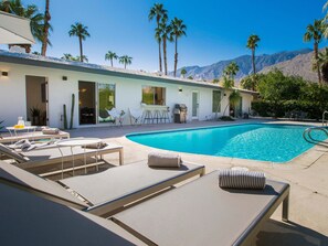 A pool area with lounge chairs, a barbecue, and a view of mountains. - Modern Marion at Twin Palms (Palm Springs)