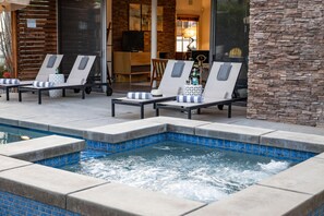 A spa area with a hot tub, lounge chairs, and a stone wall. - Lucy I'm Home (Palm Springs)