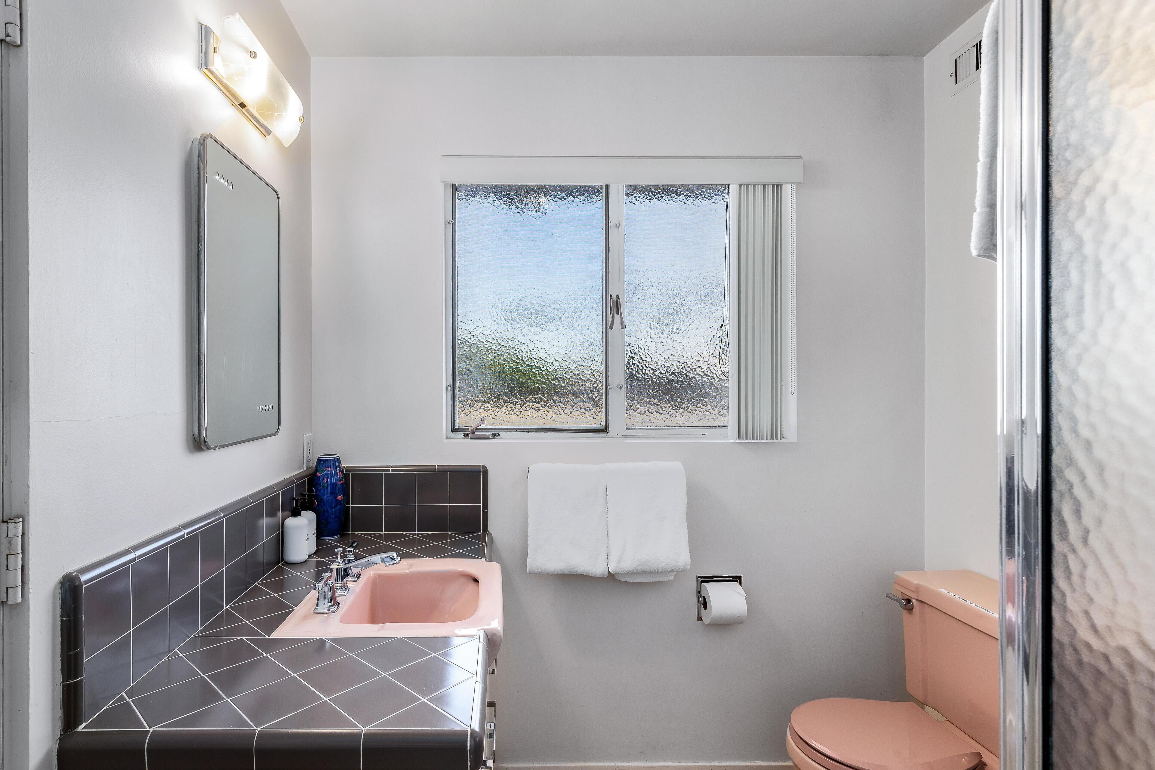 Une salle de bain équipée d’un lavabo, d’un miroir, d’un porte-serviettes, de toilettes et d’une fenêtre à vitrage dépoli.