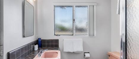 Une salle de bain équipée d’un lavabo, d’un miroir, d’un porte-serviettes, de toilettes et d’une fenêtre à vitrage dépoli.