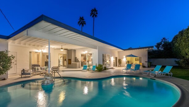 Uma casa moderna com piscina, área de estar externa e um alpendre coberto.