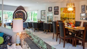 Uma zona de refeições moderna com uma parede de destaque em pedra, um candelabro e uma mesa de jantar posta para quatro pessoas.