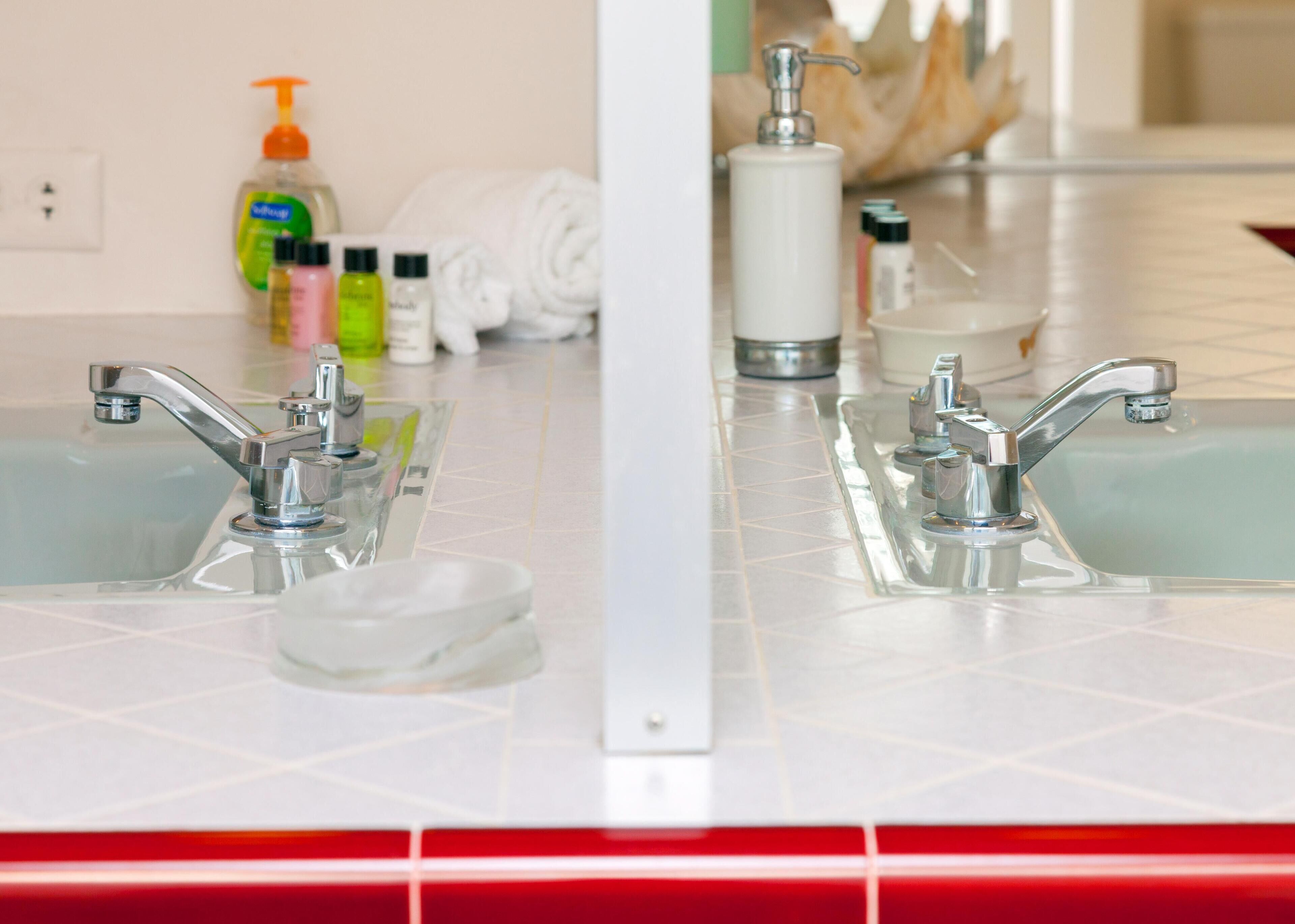 A bathroom with two sinks, a mirror, and toiletries on the counter.
