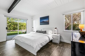 Une chambre à coucher moderne avec un grand lit, une table de chevet, une lampe et un tableau au mur.