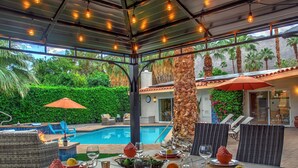 An outdoor dining area with a pool, lounge chairs, and a covered patio.