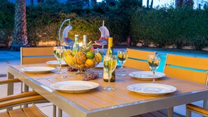 Une table à manger d’extérieur, dressée avec des assiettes, des verres et un saladier rempli de fruits.