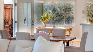 A dining area with a wooden table, wicker chairs, and a white sofa. - Hilltop Haven (Palm Springs)