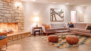 A living room with a stone fireplace, a sofa, a coffee table, and a rug. - Canary Palms (Palm Springs)