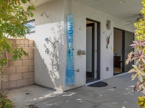 A covered outdoor area with a concrete floor, a blue decorative element, and a door leading inside. - Casa Azul (Palm Springs)