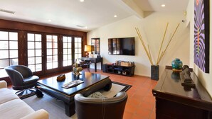 A spacious living room with a large TV, comfortable seating, and a fireplace. - Zen Dreams (Palm Springs)