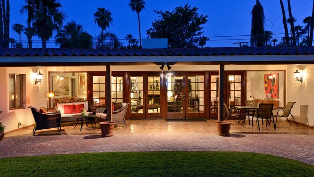 A well-lit outdoor patio area with a dining set, seating, and a view of the surrounding landscape. - Zen Dreams (Palm Springs)