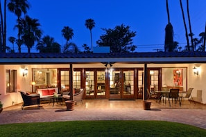 A well-lit outdoor patio area with a dining set, seating, and a view of the surrounding landscape. - Zen Dreams (Palm Springs)