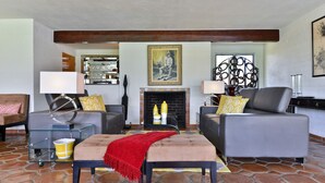 A living room with a fireplace, grey sofas, a glass coffee table, and a red throw blanket. - Zen Dreams (Palm Springs)